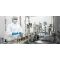 A picture of workers in a clean room working a conveyor belt with glass bottles on them
